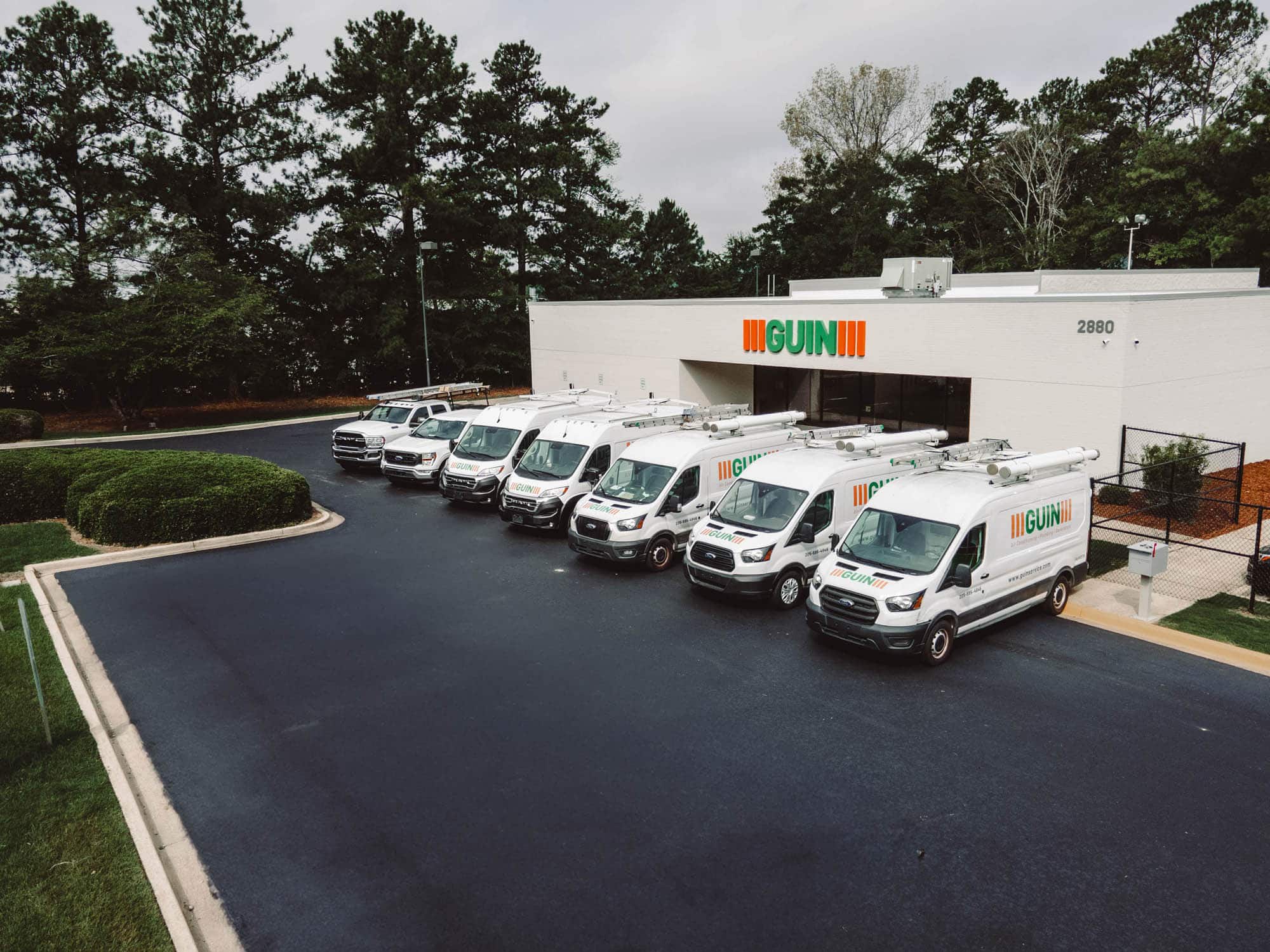Fleet of Guin service vans parked outside the company building.
